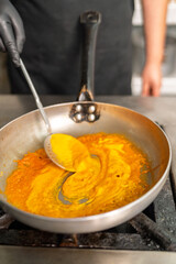 Chef mixing ingredients with skimmer in restaurant kitchen