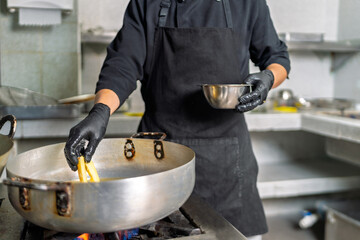 Chef frying fish in a pan in a seafood restaurant kitchen