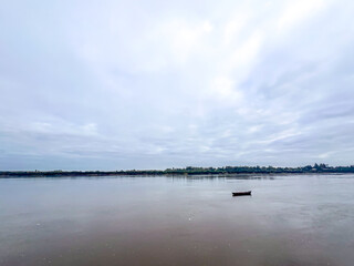 LONE BOAT ON STILL RIVER UNDER CLOUDY SKY IN ARGENTINA