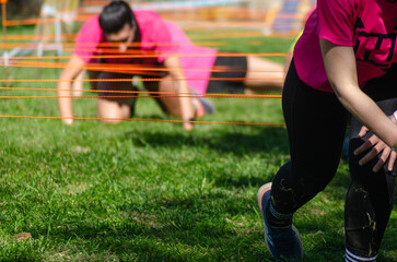 Outdoor sporting event with various difficult obstacles. Participants crawling under ropes in an obstacle course race. ocr,