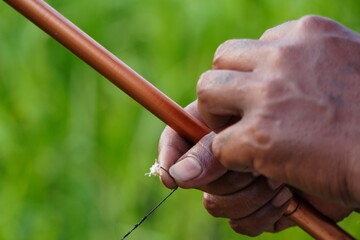 a fishermen holding a fishing rod and hook with green blurry background