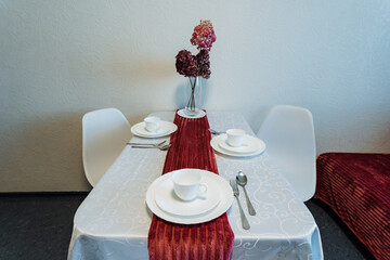A beautifully arranged table with elegant plates and a vibrant vase of fresh flowers placed on its surface, enhancing the overall aesthetic of the rooms interior design