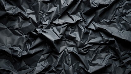 Crumpled black paper with a textured, wrinkled surface.