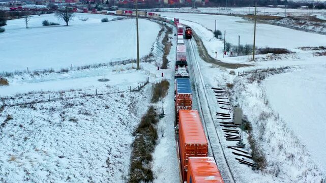 Aerial view of a long freight train moving through a snowy landscape