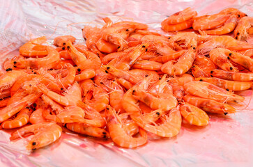 Large pile of cooked shrimp displayed on market stall with ice ready for sale