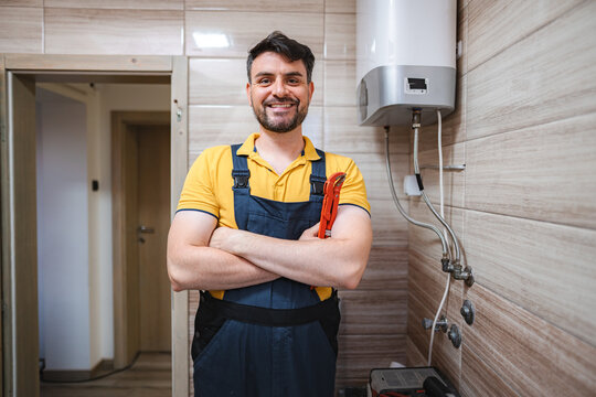 Portrait of smiling plumber holding pipe wrench in bathroom