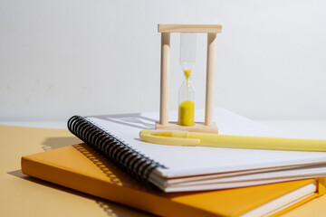 Time management concept: hourglass pencil and notepad. Time for school