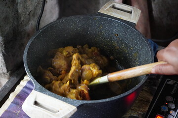 cooking chicken curry in a pot. 