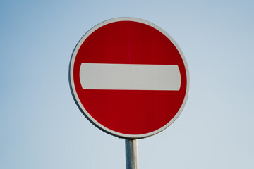 Do not enter road sign on metal pole against clear blue sky used in traffic control, symbolizing restricted access and vehicle direction regulation in public urban environments