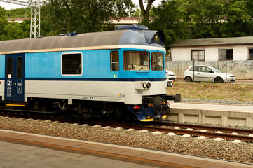 Fototapeta premium The passenger train moves along the railway station on a summer day.