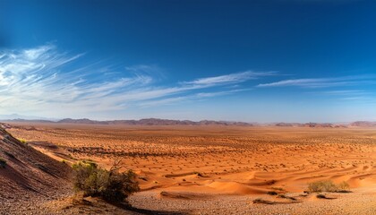 Fototapeta premium vast desert landscape under a clear blue sky with a few wispy clouds