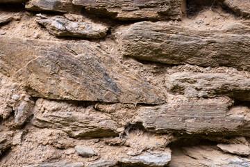 Close-up of dry stacked stone wall with earthy mortar
