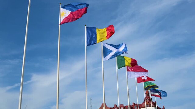 Multiple national flags waving against blue sky