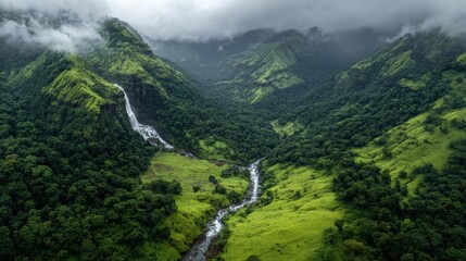Aerial view of lush green valley with cascading waterfalls and misty mountains