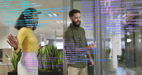Two software engineers analyzing code on glass wall in office, using tablet stylus and monitors