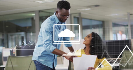 Colleagues in blue shirt, yellow top discussing cloud data at office with documents and overlays