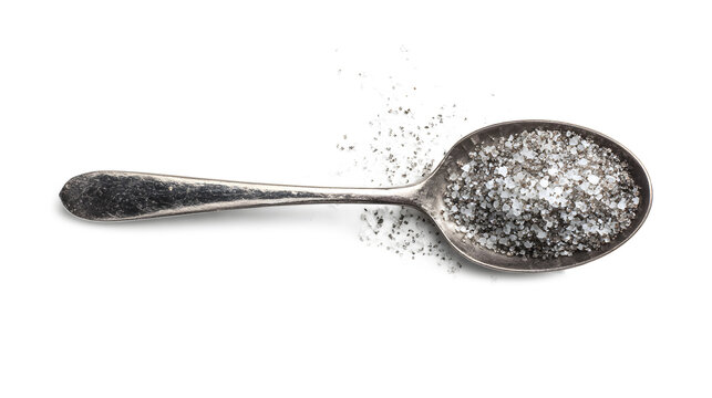 Top view of a steel teaspoon with seasoned salt isolated on a white background