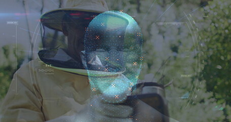 Examining beekeeper wearing suit and gloves observing hive frame in grove, with AR hologram