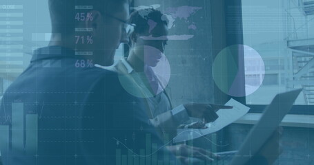 Analyzing professionals in suits reviewing charts on laptop at office window, with data overlays