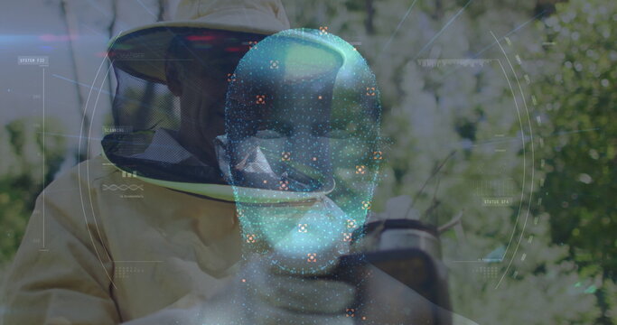 Examining beekeeper wearing suit and gloves observing hive frame in grove, with AR hologram - Powered by Adobe