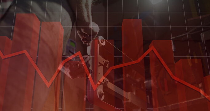 Holding skateboard, man in t-shirt and jeans analyzing red chart overlay at wooden workbench