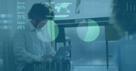 Typing man wearing business attire inputting data on laptop at office desk, with digital overlays