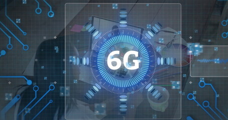 Hovering 6G holographic icon above office workstation, with laptop smartphone coffee mug supplies