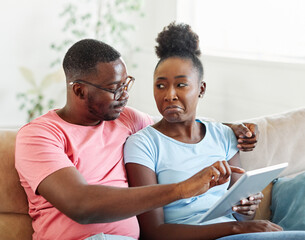 Portrait of a lovely young couple together holding a tablet on sofa at home