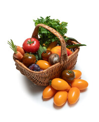 Basket with fresh vegetables and herbs on white background. Carrots, tomatoes, cucumbers, greens, mushrooms - everything for healthy diet. Isolated on white background