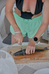 young woman cleaning and cutting fresh fish on a cutting board