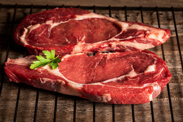 Two beef entrecotes on a grill, ready to be grilled, close-up.