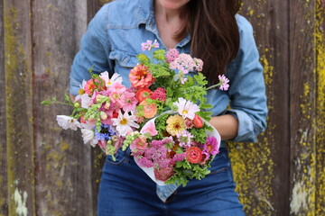 woman holding flower bouquets, flower farmer, bouquets of flowers, denim outfit 