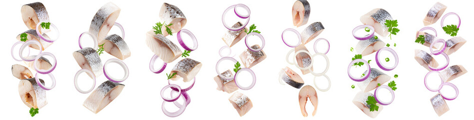 Pieces of salted herring with red onion rings and parsley falling on transparent background