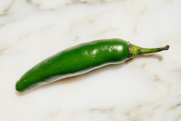 single green serrano pepper on white marble