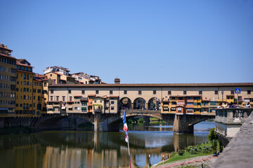 Historic Ponte Vecchio bridge with colorful buildings crossing Arno River in Florence Italy on sunny summer day