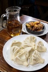 A traditional Georgian feast featuring Khinkali dumplings, pork and potato Ojakhuri served in ketsi, and a pitcher of amber wine, reflecting Georgia's culinary heritage and love for shared meals.