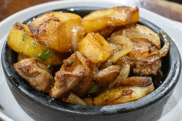 Ojakhuri served in ketsi, a traditional clay pan, features roasted meat and potatoes, with roots tracing back centuries in Georgian cuisine.