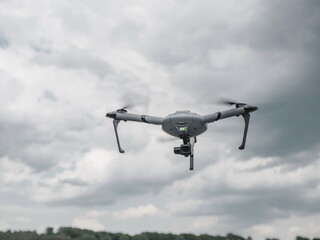Professional tricopter drone in flight against dramatic cloudy sky background