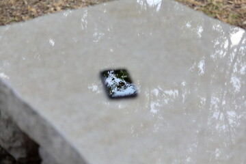 公園のピカピカの石のベンチにスマホを置いてみた