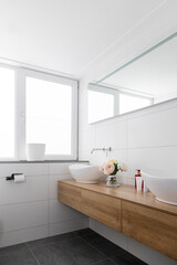 Modern bathroom with floating wooden vanity, double vessel sinks, large mirror and white tile walls