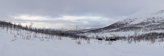 Panoramic view of snow-covered arctic mountains and valleys under cloudy winter sky