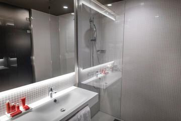 Contemporary bathroom with gray mosaic tiles, glass shower enclosure, white basin and red accent accessories