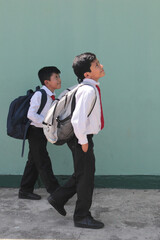 Two dark-skinned Latino boys carry their backpacks and walk back to school to study and learn