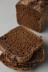 Pieces of fresh rye bread on light grey textured table, closeup
