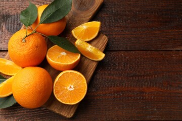 Fresh ripe oranges and leaves on wooden table, top view. Space for text