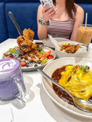 A decadent brunch featuring fried chicken atop waffles, fresh fruits, iced drinks, and a lavender latte.