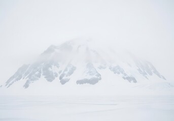 A solitary snow-covered mountain shrouded in mist and cloud evoking mystery and isolation creating