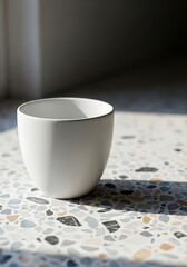 Minimalist Still Life: White Ceramic Bowl on Terrazzo Surface in Natural Light