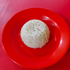 A portion of steamed white rice served on a red plate.