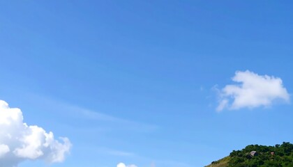 Clear blue sky with fluffy clouds and a distant hill